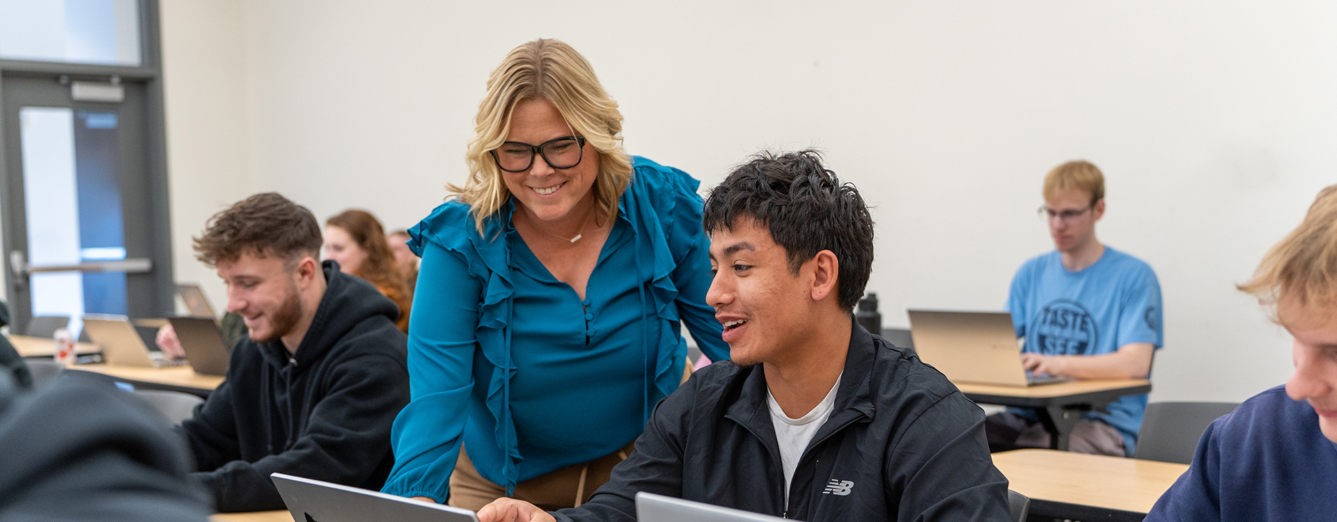 Professor talking to student while looking at laptop