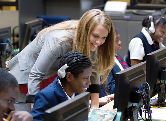 Teacher assisting students in a classroom with computers