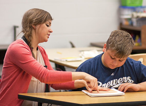 Teacher working closely with a student at a desk