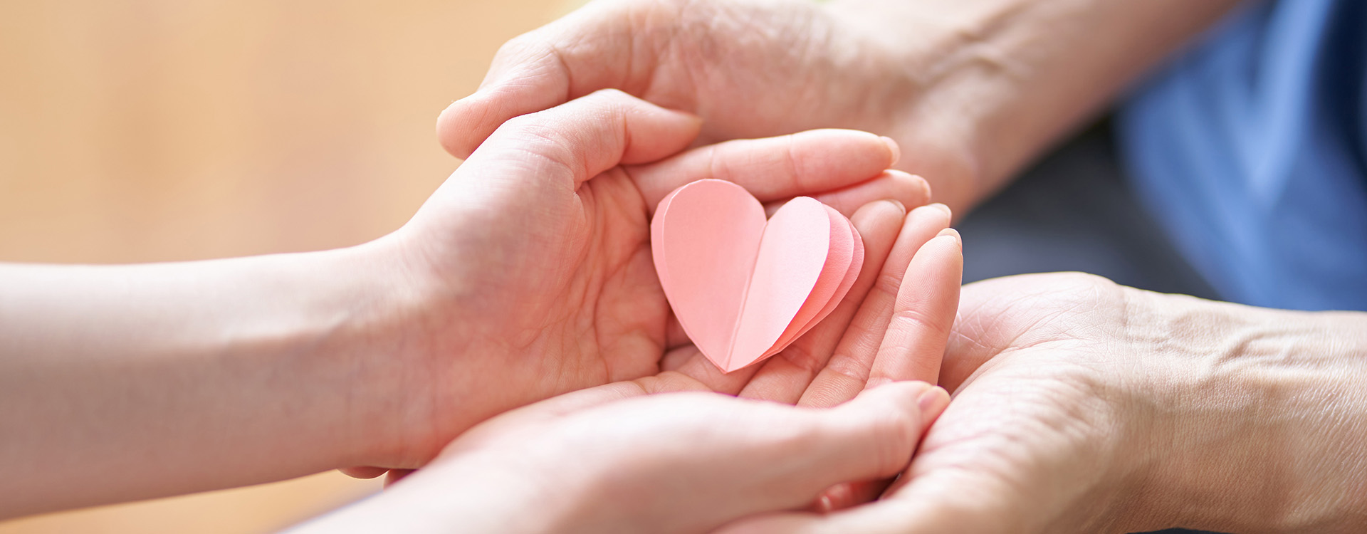 Young woman holding paper heart in hands of another person