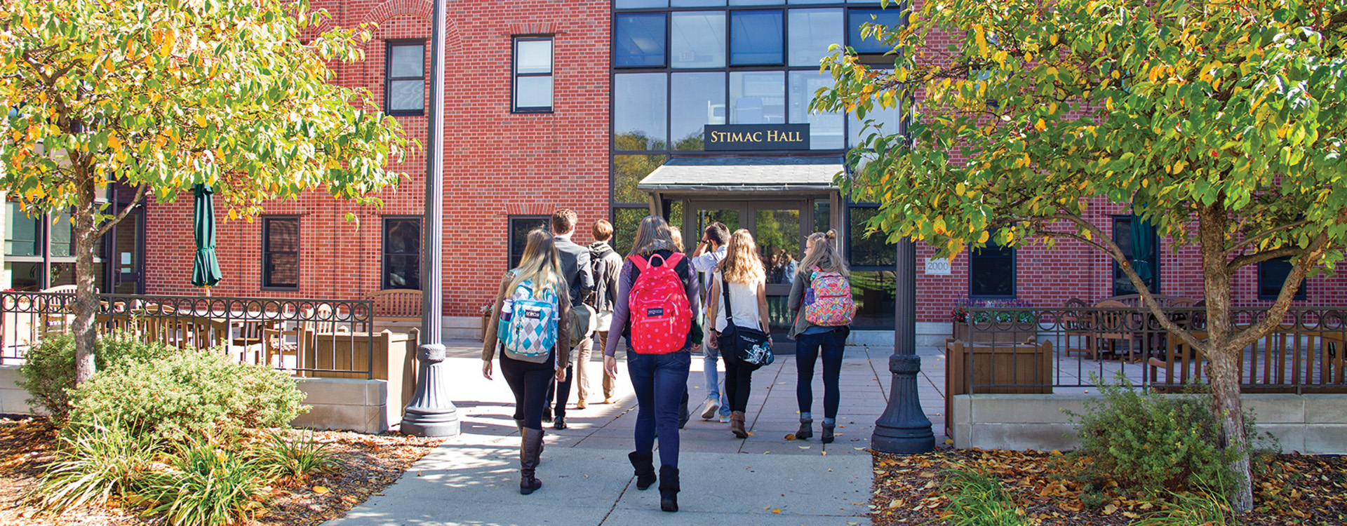 Students walking into Stimac Hall in autumn