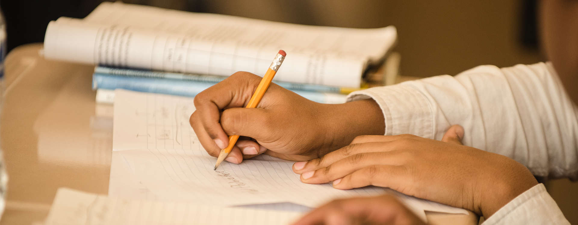 Student writing at a desk