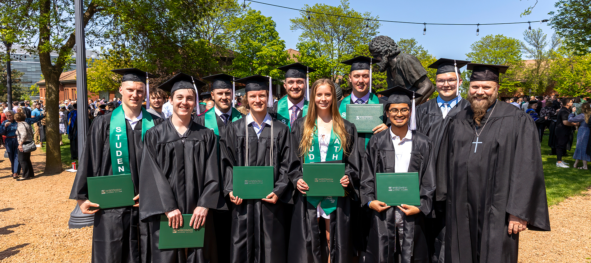 Group of grads by Divine Servant Statue on WLC Quad