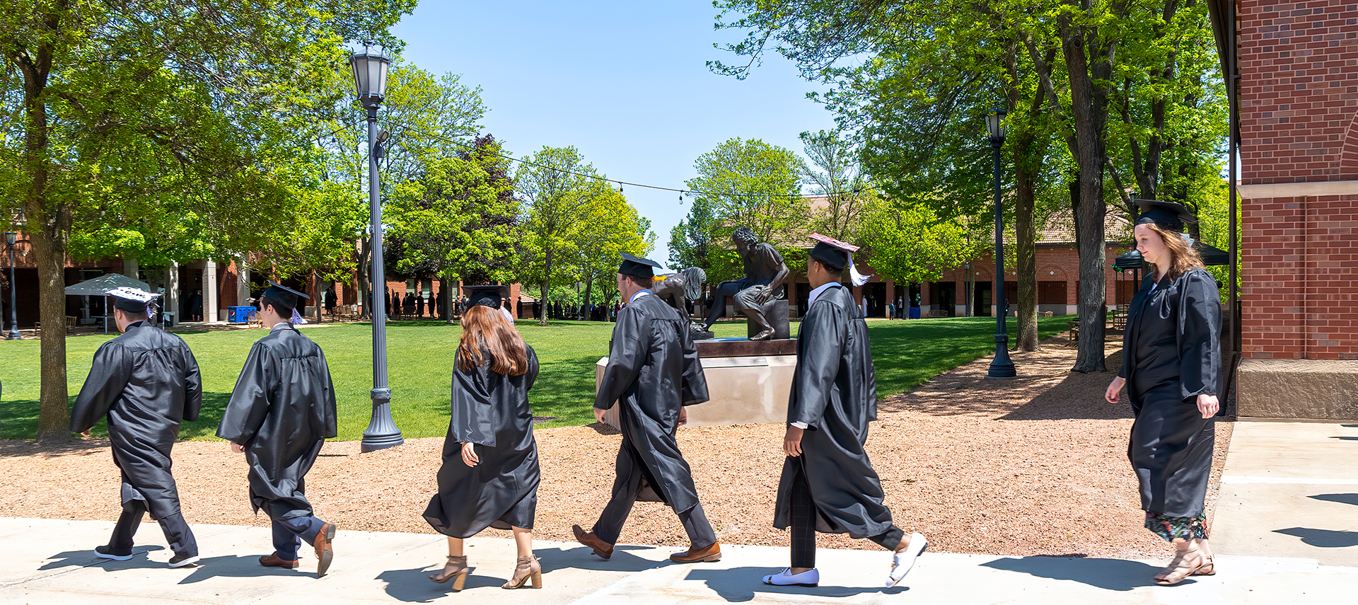 Students walking in front of Divine Servant statue