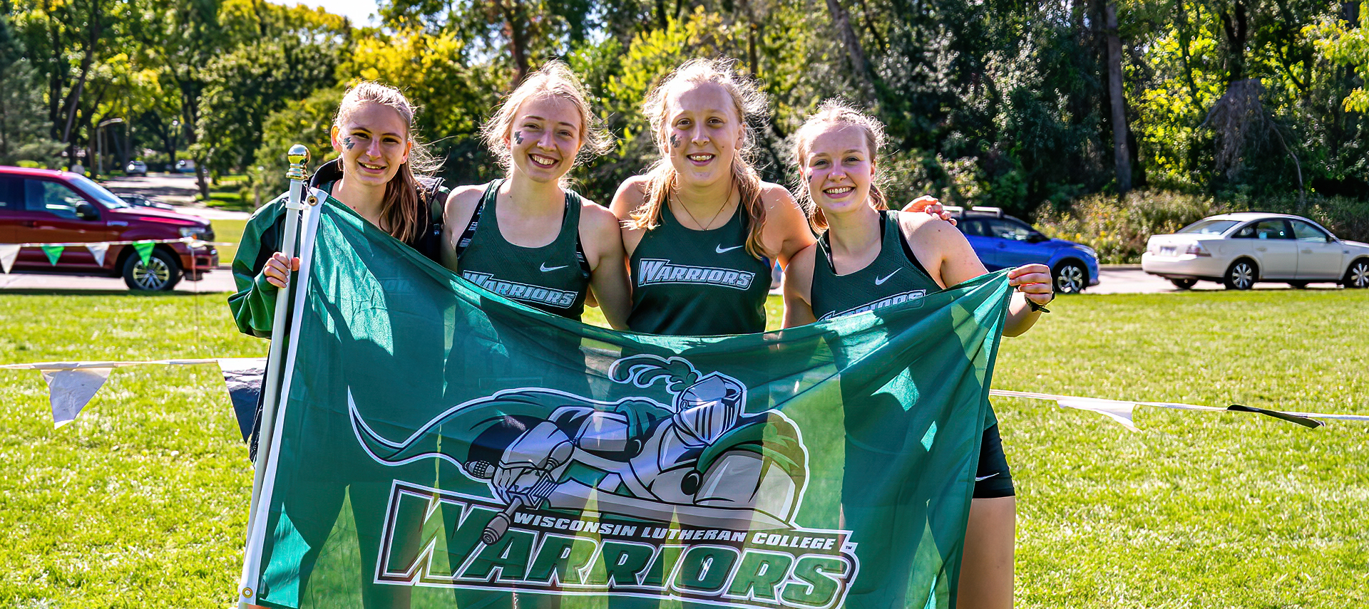 Cross-country student-athletes holding a Warriors flag