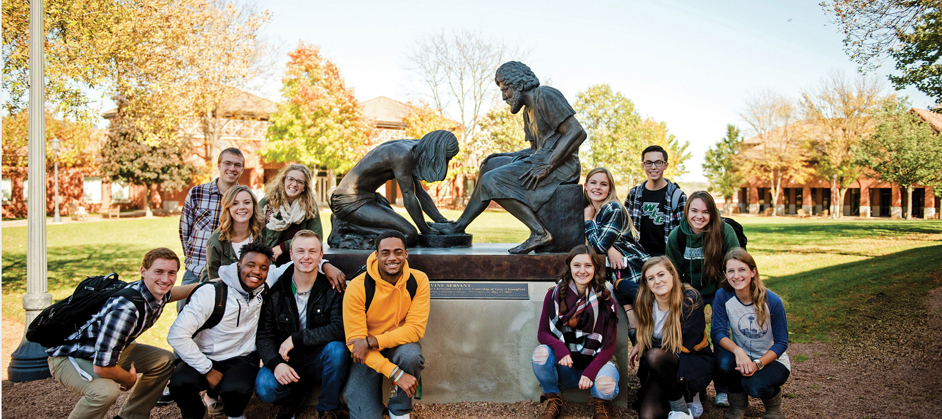 Group of students standing by Divine Servant Statue in WLC Quad