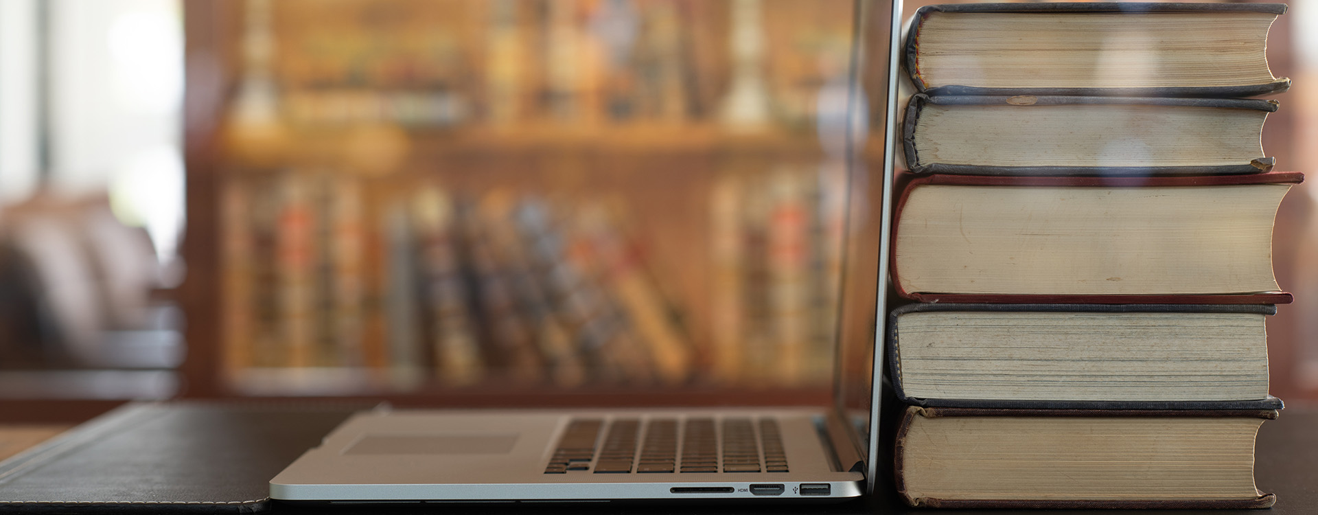 Laptop and books on table in library